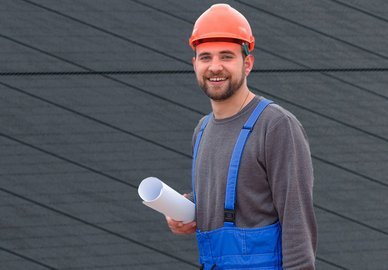 Ein Monteur mit einer Zeichnung in der Hand steht an einer Photovoltaikanlage