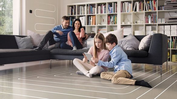 Eine Familie die in einem Wohnzimmer ist, in dem die Kinder auf dem Boden sitzen