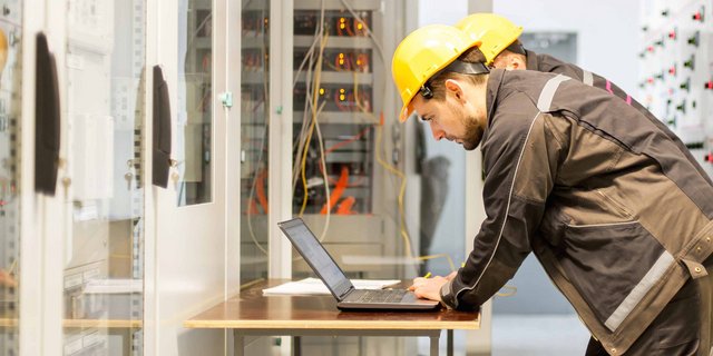 Zwei Elektroniker an einem Laptop in einem Serviceraum