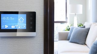 Ein modernes Smart-Home-Display zeigt die aktuelle Temperatur und Wetterbedingungen in einem hellen Wohnraum an.